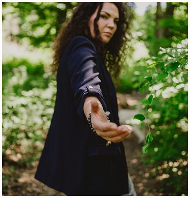 Esther Fischer steht auf einem Waldweg, der Hintergrund ist von leuchtendem Grün umgeben. Ihr Arm ist nach vorne ausgestreckt, die Hand offen, als würde sie einladen oder begleiten. Ihr Blick ist ruhig und bestimmt, ihre dunkle Kleidung kontrastiert mit dem natürlichen Umfeld. Dieses Bild vermittelt Vertrauen, Führung und Offenheit – zentrale Elemente ihrer Arbeit bei wirksam wachsen. Als Mentorin für emotionale Selbstführung, Nervensystemarbeit und therapeutisches Mentoring lädt sie Menschen ein, bewusst neue Wege zu gehen.