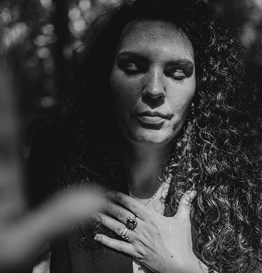 Esther Fischer steht mit geschlossenen Augen im Wald, ihre rechte Hand liegt auf ihrem Herzen. Die Sonnenstrahlen fallen sanft durch das Blätterdach, ihr Gesicht ist zur Hälfte im Schatten. Die schwarz-weiße Bildsprache betont Ruhe, innere Verbindung und Ernsthaftigkeit. Als Mentorin für Nervensystemarbeit und tiefgreifende Selbstführung bei wirksam wachsen steht Esther Fischer für bewusste Transformation, insbesondere für Frauen in verantwortungsvollen Rollen.